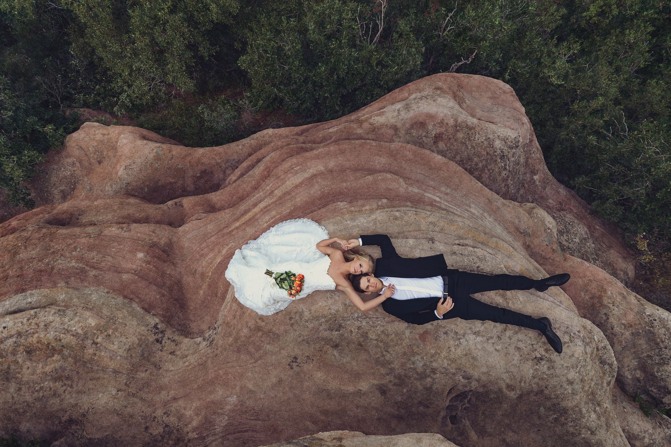 Couple lying on red rock from above