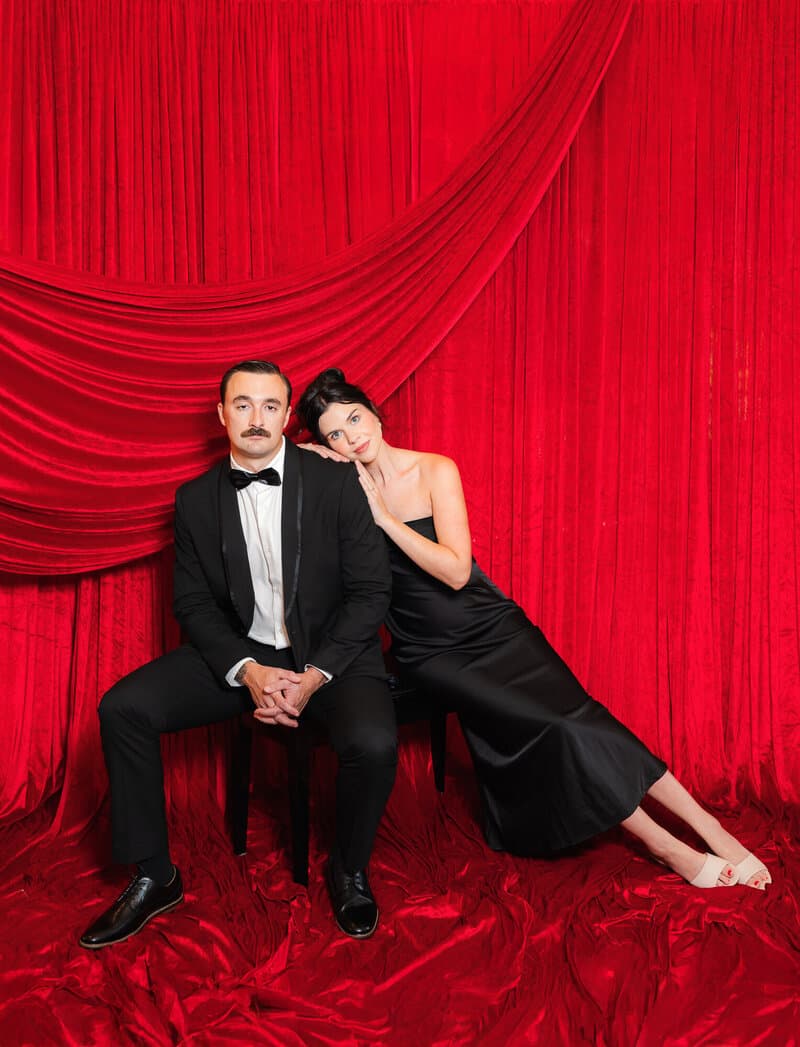 Couple seated on the red velvet set, full length