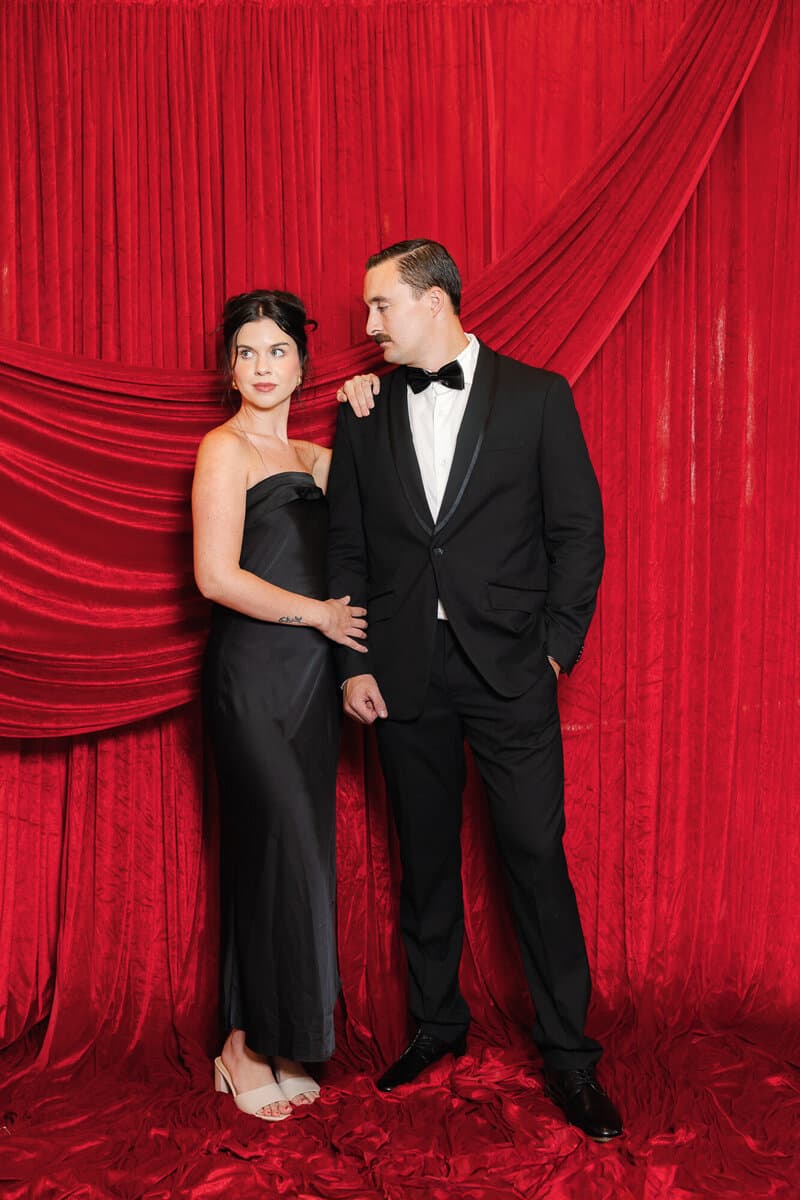 Couple in black tie, red velvet drape